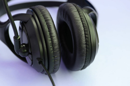 黑色耳机位于彩色粉彩紫罗兰背景上。 音乐聆听概念