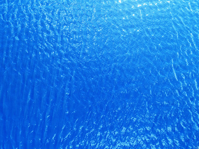 鸟瞰晶莹剔透的海水纹理。 从上面的自然蓝色背景观看。 热带海滩上的绿松波纹水反射。 蓝色的海浪。 夏天的大海。 无人驾驶飞机。 