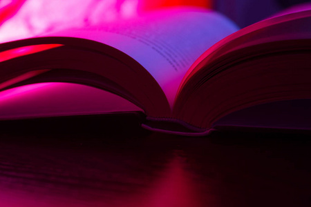 打开的书，粉红色霓虹灯在黑暗的背景上。