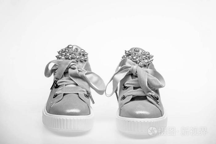 迷人的运动鞋概念。在白色背景下的可爱的鞋子。用珍珠珠装饰的女孩和妇女的鞋类。一双淡粉色女性运动鞋, 带天鹅绒缎带