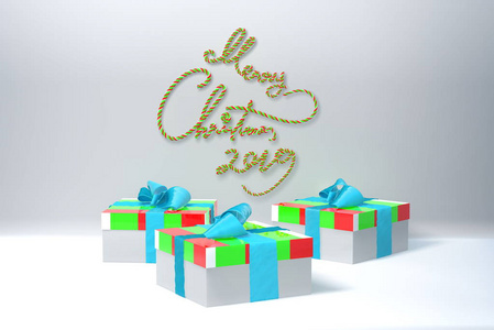 圣诞快乐2019年写的绿色和红色的条纹在白色的墙壁和三个五颜六色的礼物礼品盒旁边的弓。3d 插图