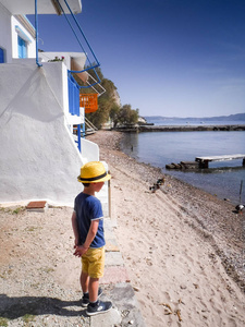 希腊米洛斯岛上的一个小男孩在海滩上的一栋住宅楼