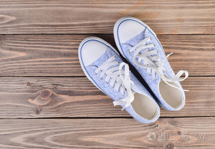女式时髦运动鞋,上面有白色鞋带,铺在软垫木地板上