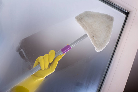 s hand with protective gloves wiping glass of window with cloth 