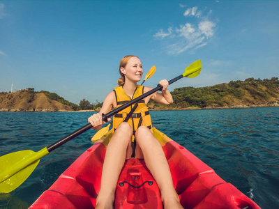 微笑的年轻女子独木舟在海上。快乐的年轻女子独木舟在海上在夏天的一天