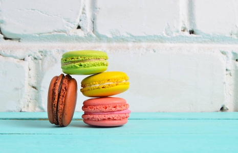 彩色饼干麦卡龙紧贴在桌子上,靠在白色砖墙的背面照片