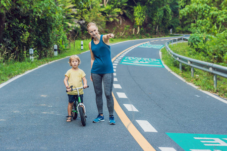 日出时在路上跑步的那个运动女人。儿子去平衡自行车。健身和健身健康概念