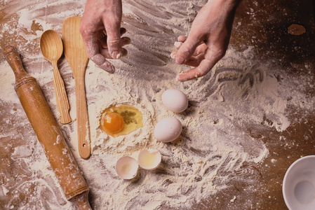 用蛋黄和面粉在木桌上做面团的人