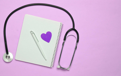 笔记本笔装饰心听诊器粉彩背景医学概念上的极简主义