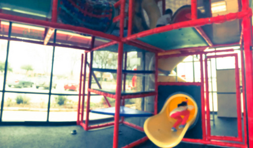 老式色调模糊运动室内游乐场，玻璃窗户和孩子们玩耍的自然光