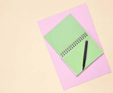 彩色纸背景上带笔的记事本。 女生日记。 顶部视图