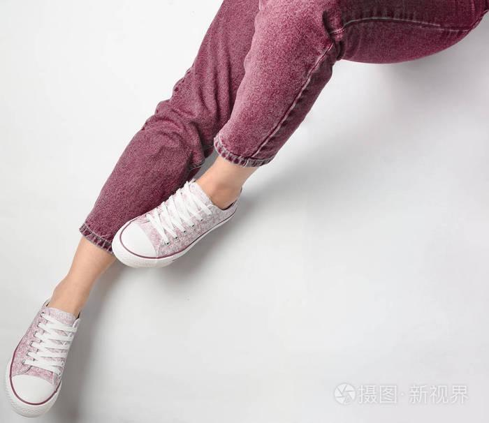 穿牛仔裤和白色背景运动鞋的女性腿. 顶级vi