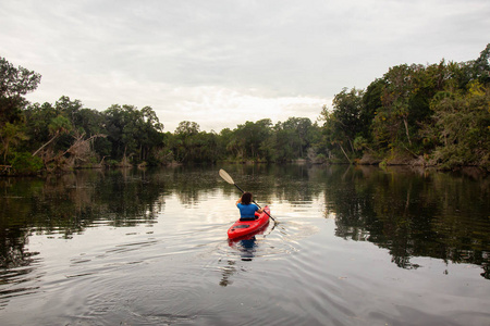 在阴天的晚上，冒险女孩在河上皮划艇。 取自位于美国奥兰多佛罗里达以西的查萨霍维茨卡河。