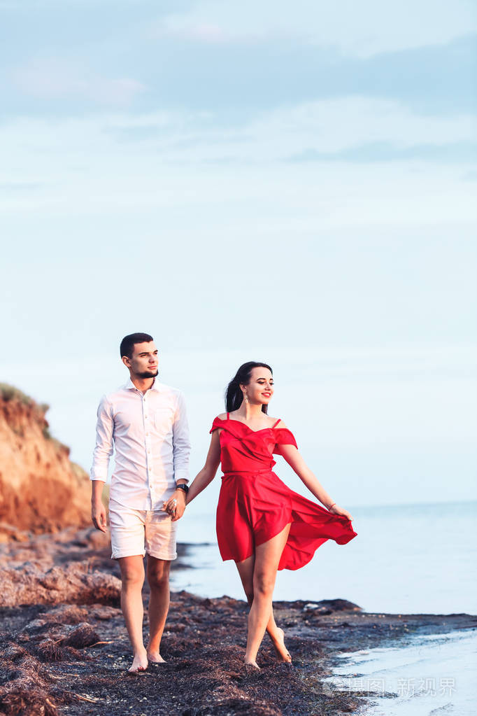 男人和女孩手牵手沿着海边散步