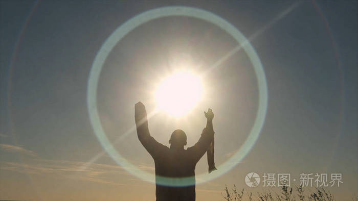 穿着长衬衫的人在日出时在田野里祈祷.太阳崇拜