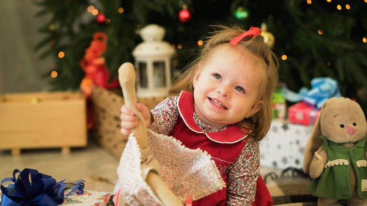 非常漂亮迷人的小女孩在红色的 jaket。在圣诞树背景上玩玩具的小女孩
