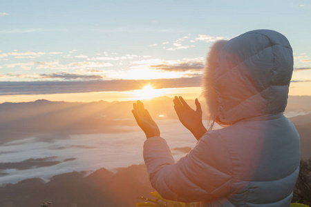 基督教妇女手祈祷上帝在山上的背景与早晨日出。 女人祈求上帝的祝福，希望有一个更好的生活。 基督教生命危机向上帝祈祷。