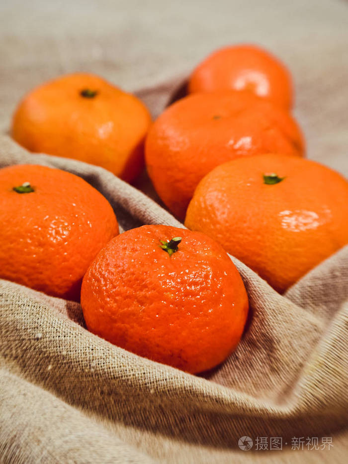 亚麻布背景上明亮的橙色橘子