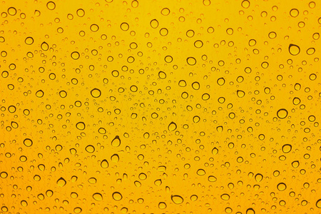 雨点落在汽车玻璃上。黄色背景。水滴图案