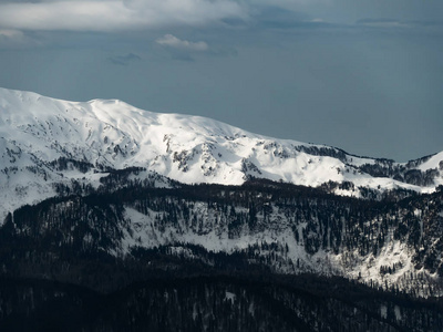 高加索山高山山峰覆盖着雪和云在冬季的一天