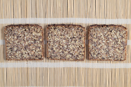 三片面包，不同的种子在竹餐巾纸背景上，俯视
