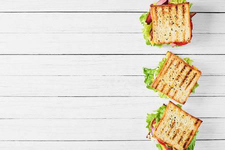 三个三明治与火腿, 生菜和新鲜蔬菜在白色背景, 顶部视图与复制空间