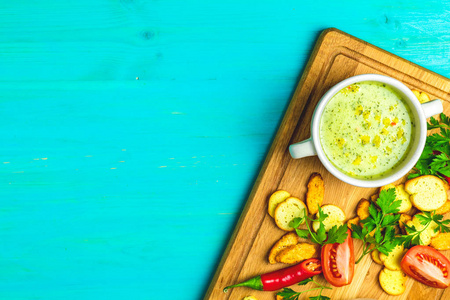健康蔬菜和豆类汤的概念。 蔬菜汤，胡萝卜鸡蛋和鸡菇奶油汤，草药，饼干和配料。 蓝色绿松石木板上的俯视图