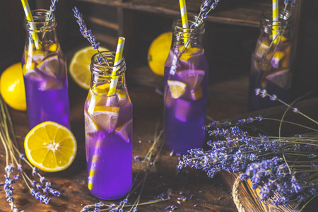 新鲜的紫罗兰鸡尾酒,柠檬冰和薰衣草饮料瓶玻璃在一个黑暗的古老乡村