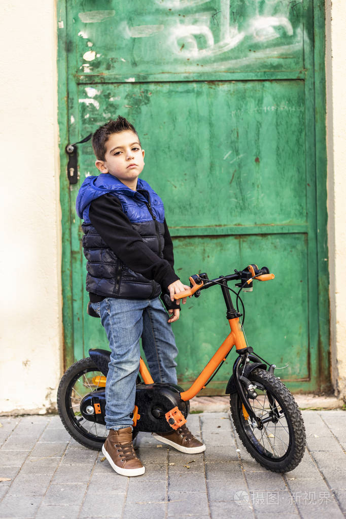 小男孩骑着自行车在引擎盖上