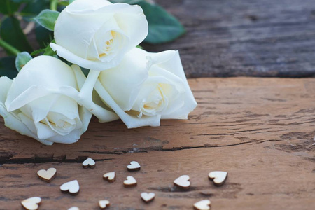 美丽的白色和粉红色的新鲜玫瑰花和迷你心在木制背景软调情人节概念
