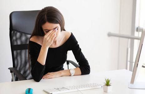 头部疼痛精疲力竭的年轻女子在电脑上工作后感到头部疼痛。超负荷工作的概念