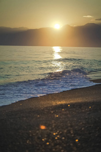 金色飞溅的泡沫海波在夕阳的天空和柔和的阳光背景。 垂直彩色摄影。