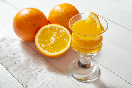 一杯新鲜橙汁和水果放在白色的木桌上。
