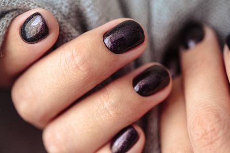 华丽的指甲，深紫色，嫩色指甲油特写照片。 女性双手翻着简单的便服背景