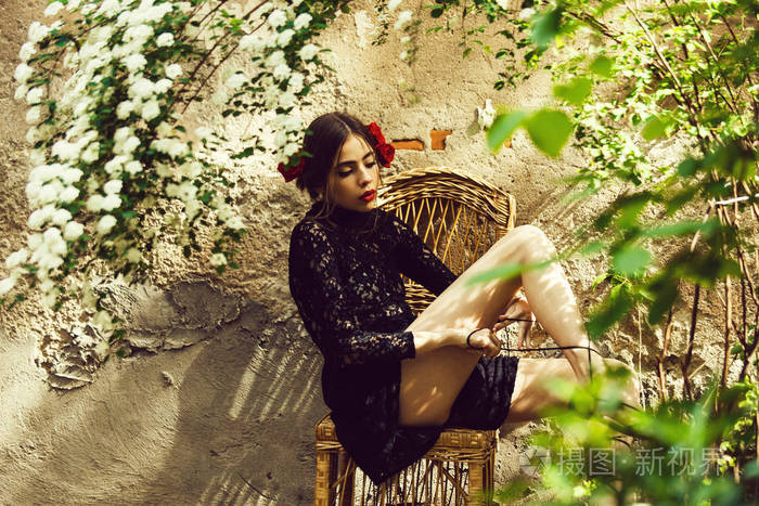 阳光明媚的日子在藤椅上绑鞋带的女人