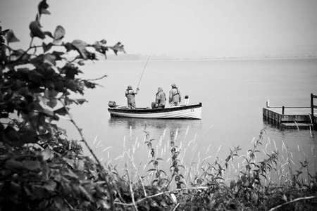 渔民在湖上的船上，雨天黑白照片。
