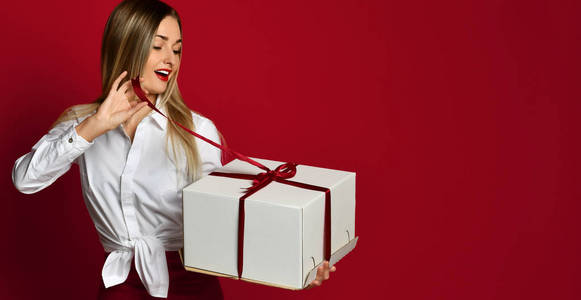 年轻的金发碧眼的女人打开白色的盒子礼物礼物微笑