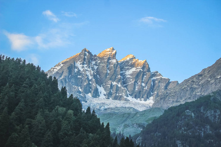 日出在雪山峰上。 前景中有冰川和松林的山