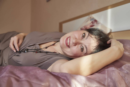 内紫床房里漂亮的中年女人. 家里的女士一天内休息一下.