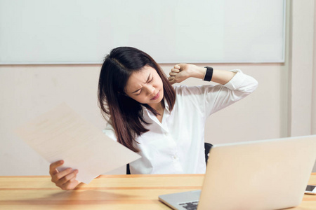 女人因为电脑和工作很长时间而背痛。 这可能是办公室综合征的原因。