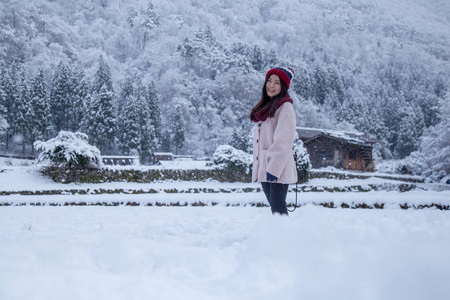 快乐的亚洲女孩是在白川村的雪中微笑，包括传统的加绍风格和联合国教科文组织世界遗产之一，日本吉夫