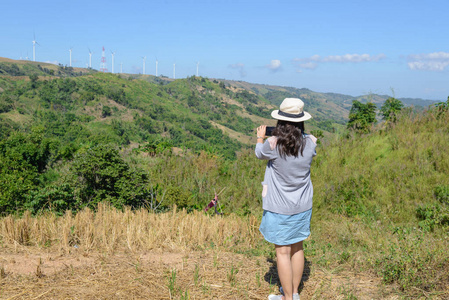 年轻的亚洲女游客用智能手机拍照山景
