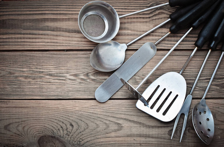 厨房用于烹饪，由筛子叉子勺子勺子铲子组成，用于木制桌子上的煎炸。上景。复制空间。
