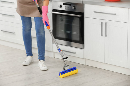 女人在厨房用拖把清洁地板