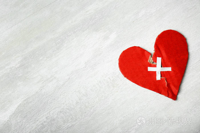 撕裂的纸板心脏与灰色背景上的粘合垫连接在一起关系问题