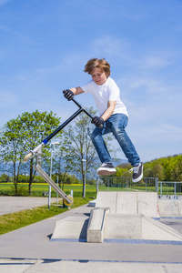 小男孩在溜冰场用推式滑板车跳得很开心