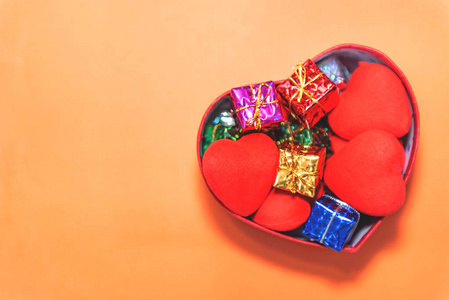 顶部的开放式红色礼品盒与心形和小礼品盒内在橙色背景。孤立背景的假日概念