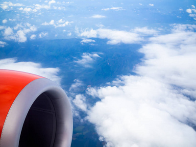 红色飞机的喷气式发动机，从乘客的窗口看云和蓝天背景与复制空间。