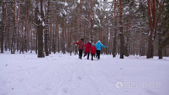 幸福的爸爸妈妈带着孩子在冬天的森林里跑来跑去。冬天, 父母和孩子们在雪园里玩耍。幸福的家庭走在圣诞森林里