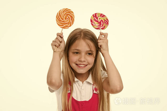 滑稽的女孩微笑与漩涡奶糖.小男孩用糖果在白色的树枝上微笑.